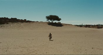 Movie still from “Oedipus Rex” (1967), directed by Pier Paolo Pasolini – A man walking across a sandy beach with a tree in the background; Extreme Wide shot, High angle
