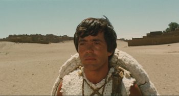 Movie still from “Oedipus Rex” (1967), directed by Pier Paolo Pasolini – A man in a native american costume with a large backpack; Close Up shot, Over the shoulder angle