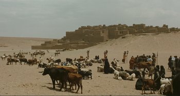 Movie still from “Oedipus Rex” (1967), directed by Pier Paolo Pasolini – A group of people standing on top of a dirt field; Extreme Wide shot, High angle