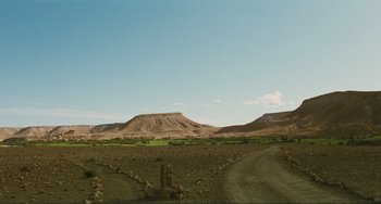 Movie still from “Oedipus Rex” (1967), directed by Pier Paolo Pasolini – A dirt road in the middle of a desert with mountains in the background; Extreme Wide shot, Low angle