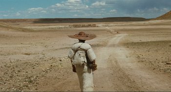 Movie still from “Oedipus Rex” (1967), directed by Pier Paolo Pasolini – A person in a hat is standing in the desert; Wide shot, High angle