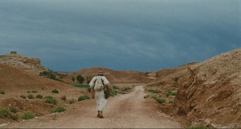 Movie still from “Oedipus Rex” (1967), directed by Pier Paolo Pasolini – A man walking down a dirt road carrying a backpack; Extreme Wide shot, Low angle