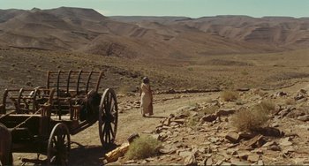 Movie still from “Oedipus Rex” (1967), directed by Pier Paolo Pasolini – A man standing next to an old wagon on a dirt road; Extreme Wide shot, High angle