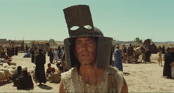 Movie still from “Oedipus Rex” (1967), directed by Pier Paolo Pasolini – A man wearing a helmet and a body suit in the desert; Close Up shot, Low angle