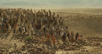 Movie still from “Oedipus Rex” (1967), directed by Pier Paolo Pasolini – A large group of people sitting on top of a rocky hill; Extreme Wide shot, High angle