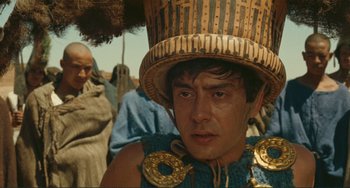 Movie still from “Oedipus Rex” (1967), directed by Pier Paolo Pasolini – A man wearing a straw hat and a blue and gold outfit; Close Up shot, Low angle