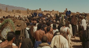 Movie still from “Oedipus Rex” (1967), directed by Pier Paolo Pasolini – A large group of people gathered together in the middle of the desert; Extreme Wide shot, High angle