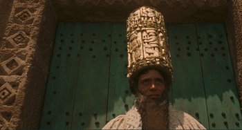 Movie still from “Oedipus Rex” (1967), directed by Pier Paolo Pasolini – A man wearing a gold hat and a white coat; Close Up shot, Low angle