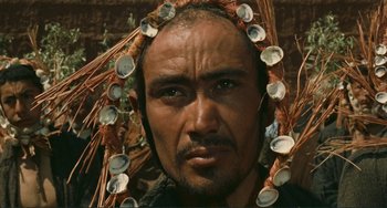 Movie still from “Oedipus Rex” (1967), directed by Pier Paolo Pasolini – A person wearing a headdress; Close Up shot, High angle