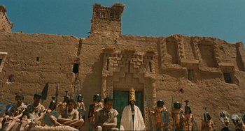 Movie still from “Oedipus Rex” (1967), directed by Pier Paolo Pasolini – A group of people standing in front of an old building; Extreme Wide shot, Low angle