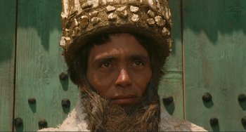 Movie still from “Oedipus Rex” (1967), directed by Pier Paolo Pasolini – A man with a beard wearing a gold hat; Close Up shot, Low angle