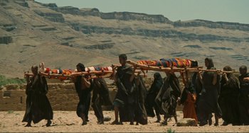 Movie still from “Oedipus Rex” (1967), directed by Pier Paolo Pasolini – A group of people walking across the desert carrying blankets; Extreme Wide shot, High angle