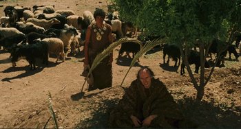 Movie still from “Oedipus Rex” (1967), directed by Pier Paolo Pasolini – A man sitting under a tree next to a herd of sheep; Wide shot, High angle