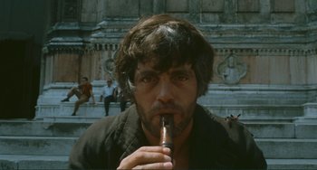 Movie still from “Oedipus Rex” (1967), directed by Pier Paolo Pasolini – A man is smoking a cigarette while sitting on some steps; Close Up shot, Low angle