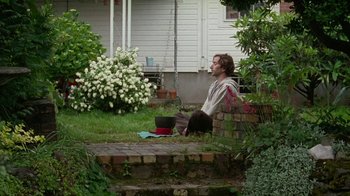 Movie still from “Old Joy” (2006), directed by Kelly Reichardt – A man sitting on the ground in a yard; Wide shot, High angle
