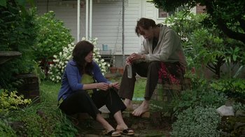 Movie still from “Old Joy” (2006), directed by Kelly Reichardt – A man and a woman sitting on a brick wall outside; Medium shot, Low angle