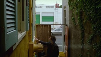 Movie still from “Old Joy” (2006), directed by Kelly Reichardt – A man standing in a doorway next to a building; Wide shot, Low angle