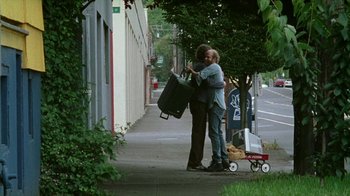 Movie still from “Old Joy” (2006), directed by Kelly Reichardt – A man and a woman hugging on the side of the street; Wide shot, Low angle