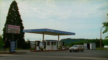 Movie still from “Old Joy” (2006), directed by Kelly Reichardt – A gas station with a car parked on the side of the road; Extreme Wide shot, High angle