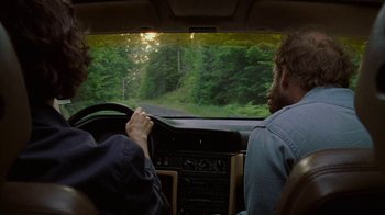 Movie still from “Old Joy” (2006), directed by Kelly Reichardt – Two men in the drivers seat of a car driving down a road; Medium shot, Over the shoulder angle