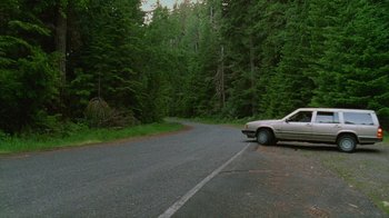 Movie still from “Old Joy” (2006), directed by Kelly Reichardt – A car parked on the side of a road near a forest; Extreme Wide shot, High angle