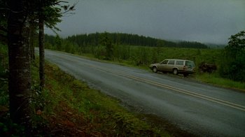Movie still from “Old Joy” (2006), directed by Kelly Reichardt – A car driving down a road near a forest; Extreme Wide shot, High angle