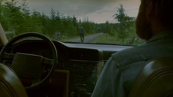 Movie still from “Old Joy” (2006), directed by Kelly Reichardt – A man walking down a road in the woods; Wide shot, Over the shoulder angle
