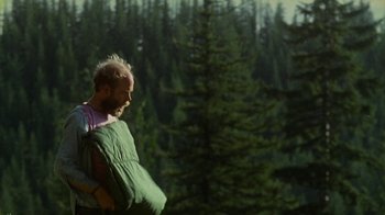 Movie still from “Old Joy” (2006), directed by Kelly Reichardt – A man in a green sleeping bag in front of a forest; Medium shot, Over the shoulder angle