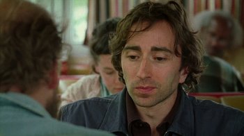 Movie still from “Old Joy” (2006), directed by Kelly Reichardt – A person sitting at a table; Close Up shot, Over the shoulder angle