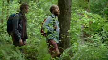 Movie still from “Old Joy” (2006), directed by Kelly Reichardt – A man with a beard is walking through the woods; Medium shot, Over the shoulder angle