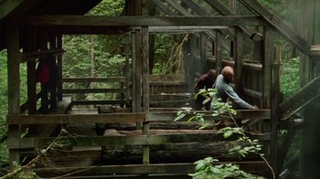 Movie still from “Old Joy” (2006), directed by Kelly Reichardt – Two people sitting on a wooden bench in a forest; Extreme Wide shot, Low angle