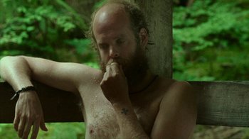 Movie still from “Old Joy” (2006), directed by Kelly Reichardt – A man with a beard is leaning against a pole; Close Up shot, High angle