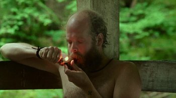 Movie still from “Old Joy” (2006), directed by Kelly Reichardt – A man with a beard is lighting a cigarette; Medium shot, Low angle