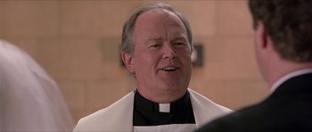 Movie still from “Old School” (2003), directed by Todd Phillips – A man in a priest's outfit smiling for the camera; Close Up shot, Low angle