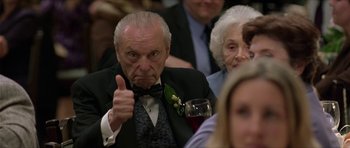 Movie still from “Old School” (2003), directed by Todd Phillips – An older man giving a thumbs up at an event; Medium shot, Low angle