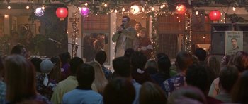Movie still from “Old School” (2003), directed by Todd Phillips – A man singing into a microphone on a stage; Wide shot, Over the shoulder angle