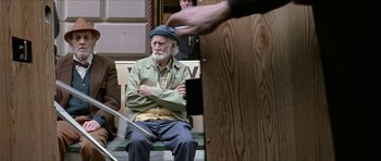 Movie still from “Old School” (2003), directed by Todd Phillips – An older man sitting on a bench with his arms crossed; Medium shot, Over the shoulder angle
