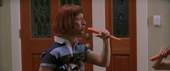 Movie still from “Old School” (2003), directed by Todd Phillips – A woman holding a cat and a carrot in front of a door; Medium shot, Low angle