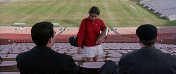 Movie still from “Old School” (2003), directed by Todd Phillips – A woman in a red shirt is holding a book; Wide shot, High angle
