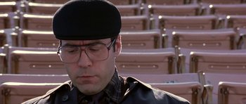 Movie still from “Old School” (2003), directed by Todd Phillips – A man wearing glasses and a hat sitting in front of some steps; Close Up shot, Low angle