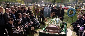 Movie still from “Old School” (2003), directed by Todd Phillips – A group of people sitting around a grave with flowers; Wide shot, High angle
