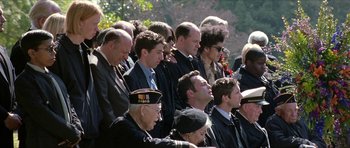 Movie still from “Old School” (2003), directed by Todd Phillips – A group of men in suits and ties sitting next to each other in front of trees; Medium shot, Over the shoulder angle