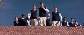 Movie still from “Old School” (2003), directed by Todd Phillips – A group of men standing next to each other in front of rows of seats; Wide shot, Low angle