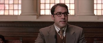 Movie still from “Old School” (2003), directed by Todd Phillips – A man in a brown suit and glasses is sitting in front of a microphone; Close Up shot, Low angle