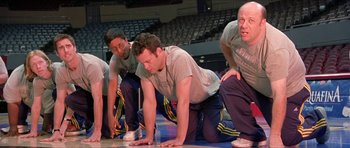 Movie still from “Old School” (2003), directed by Todd Phillips – A group of men are doing push - ups in a gym; Medium shot, High angle