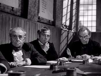 Movie still from “Oliver Twist” (1948), directed by David Lean – A group of people sitting at a table; Medium shot, High angle
