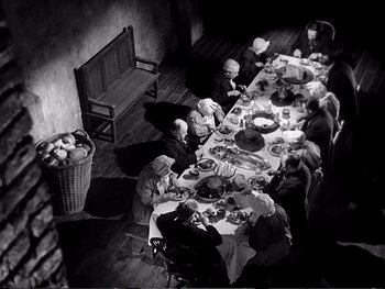 Movie still from “Oliver Twist” (1948), directed by David Lean – A group of people sitting around a long dinner table; Wide shot, High angle