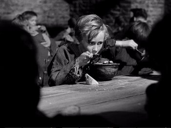 Movie still from “Oliver Twist” (1948), directed by David Lean – Black and white photograph of a boy eating a bowl of food; Medium shot, High angle