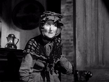 Movie still from “Oliver Twist” (1948), directed by David Lean – An old woman wearing a dress and a hat; Medium shot, Low angle