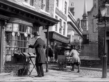Movie still from “Oliver Twist” (1948), directed by David Lean – An old photo of a man and a woman on the street; Wide shot, Low angle